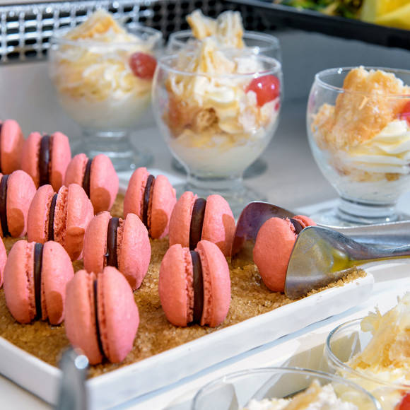 Close-up of a dessert buffet featuring pink macarons and desserts