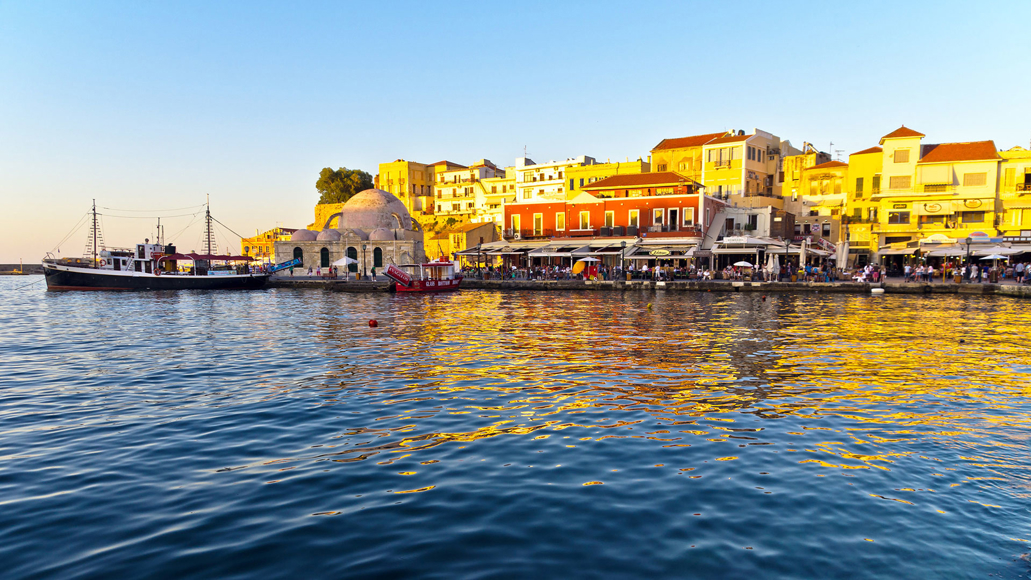 Chania Old Venetian Harbor with waterfront restaurants and shops at sunset
