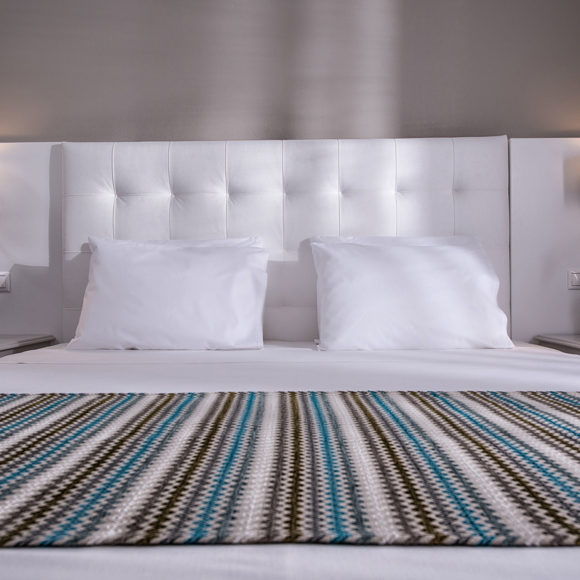 Front view of a double bed with wall-mounted reading lamps 
