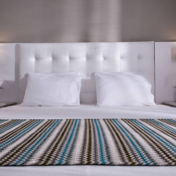 Front view of a double bed with wall-mounted reading lamps 