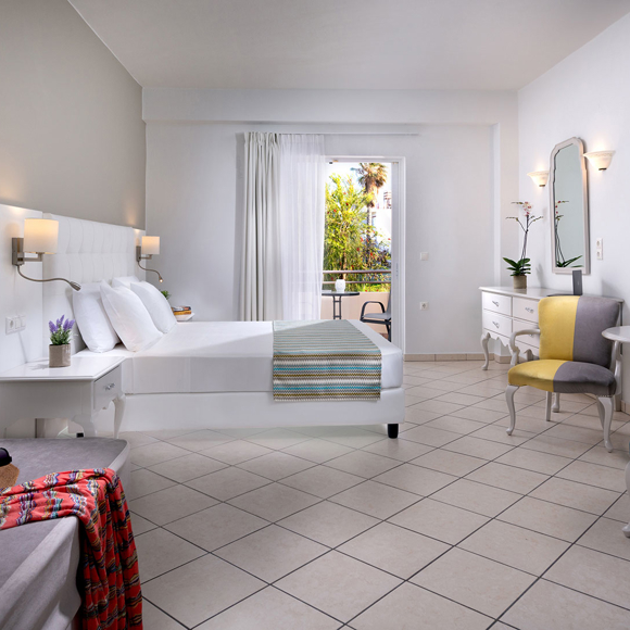 Double room with white decor, seating area and balcony access with garden view
