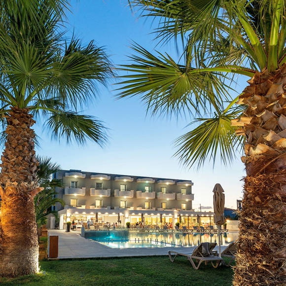 Dore hotel building with balconies, outdoor pool, sun loungers and palm trees in the foreground