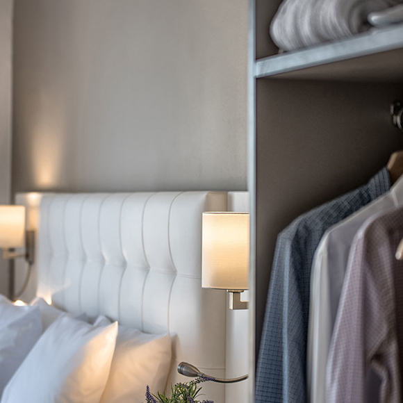 Close-up of white headboard next to open wardrobe