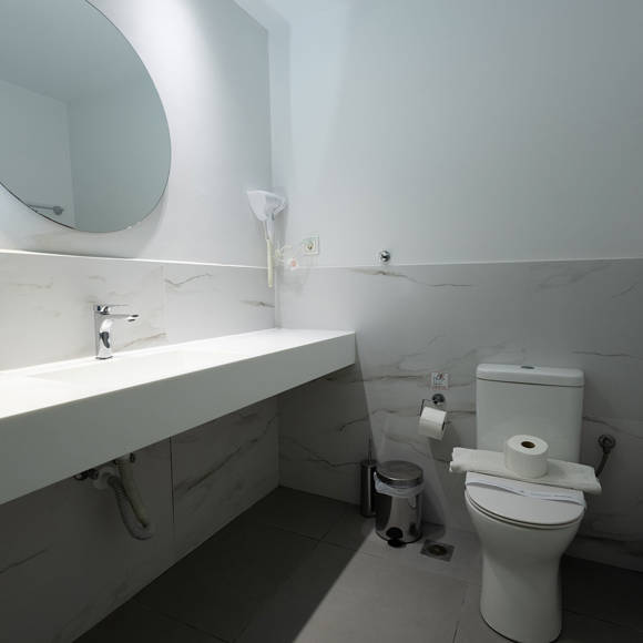 Bright bathroom with large mirror, white countertop and modern toilet