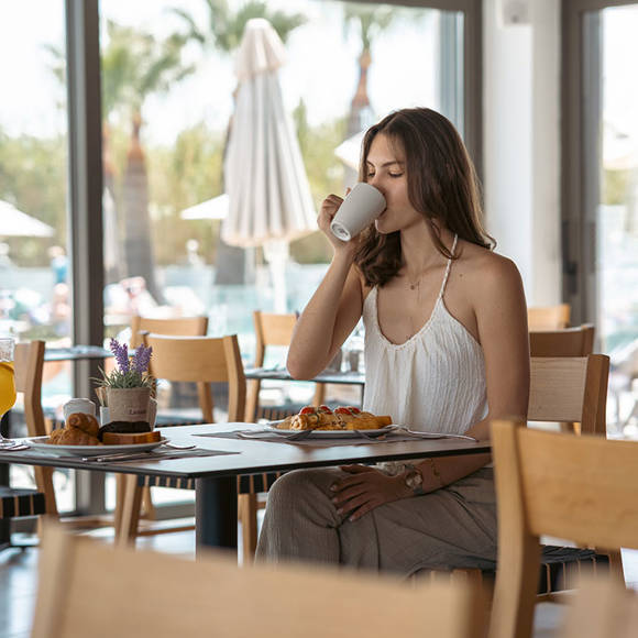 Young woman enjoying a hot drink during breakfast at the hotel restaurant