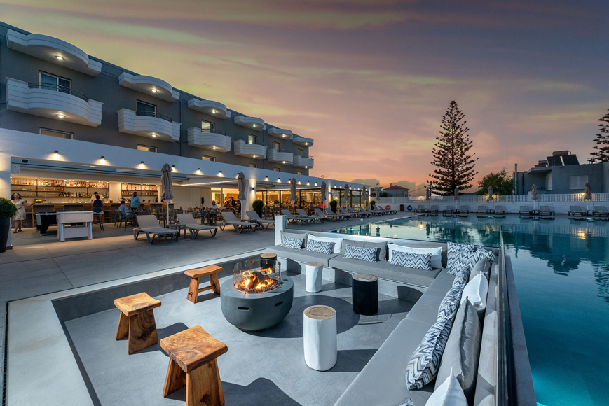 Outdoor lounge area with firepit by the pool at sunset