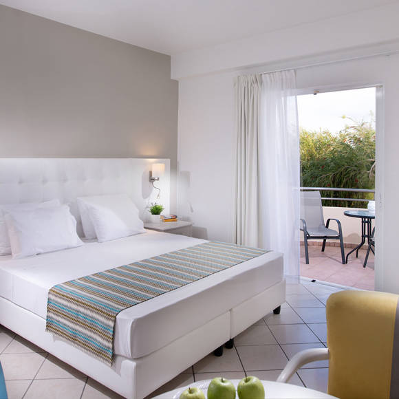 Double room with king sized bed, desk setup and balcony facing greenery