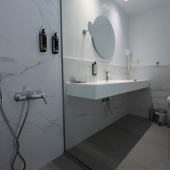 Modern bathroom with walk-in shower, large mirror and wall mounted toiletries