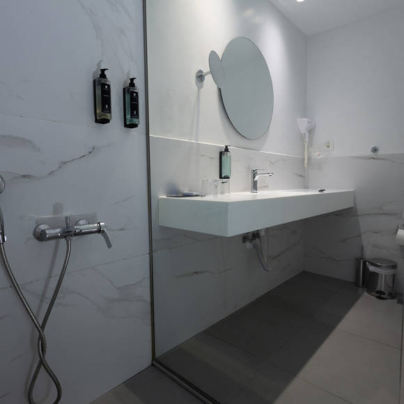 Modern bathroom with walk-in shower, large mirror and wall mounted toiletries